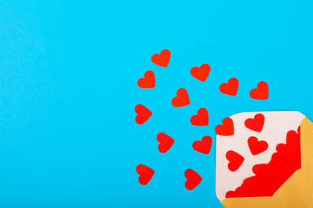 Open beige envelope with red heart shapes by copy space on blue background. love and valentine present.の写真素材