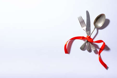 Overhead view of cutlery tied tightly with red ribbon with copy space on white background. valentine and dining.の写真素材