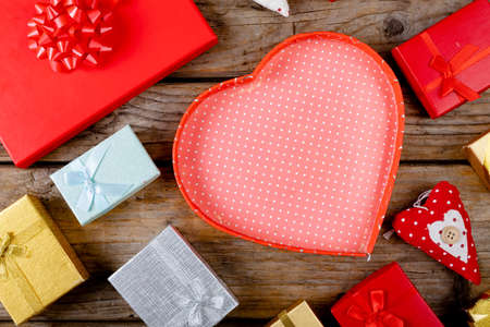 Overhead view of empty red heart shape gift box with copy space amidst presents on wooden table. love and valentine.の写真素材