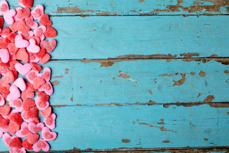 Overhead view of sweet pink and red heart shape candies on blue wooden table with copy space. love and valentine candies.の写真素材
