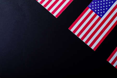 Overhead view of america flags with red and white stripes along with stars over black background....
