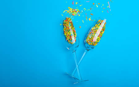Overhead view of champagne flutes with confetti by copy space over blue background. love and valentine celebration.の写真素材
