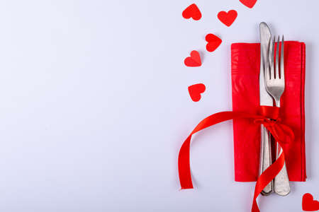 Overhead view of cutlery tied with red ribbon on napkin by copy space over white background. valentine and dining.の写真素材