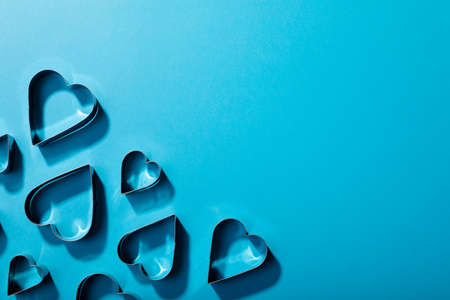 Overhead view of heart shaped cookie cutters arranged over blue background with copy space. valentine's day and love concept.の写真素材