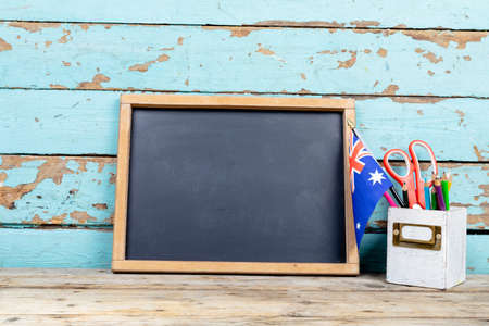 Blank writing slate by australian flag and desk organizer against wooden wall, copy space. independence day, national flag and patriotism.の写真素材