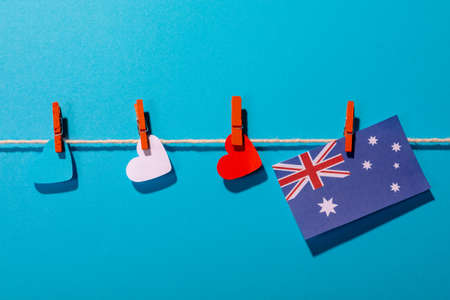Australia flag with heart shaped papers on clothesline over blue background with copy space. independence day, love and patriotism.の写真素材