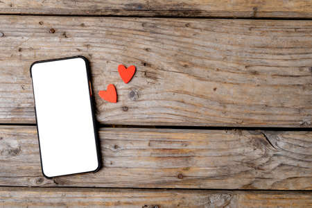 Overhead view of white screen on smart phone by heart shaped decoration on table, copy space. valentine's day, wireless technology and love concept.の写真素材