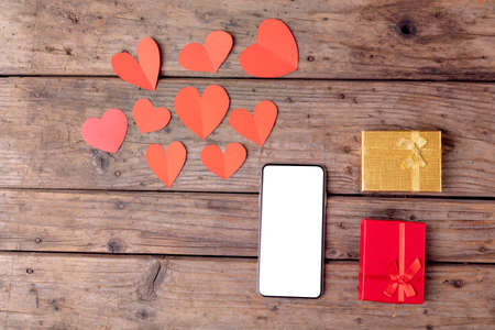 Overhead view of smart phone by valentine gifts and heart shaped decoration on table, copy space. valentine&#39;s day, wireless technology and love concept.の写真素材