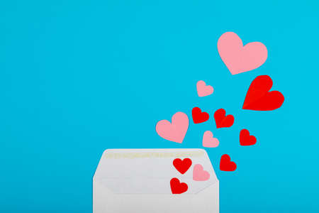 Overhead view of pink and red hearts coming from envelope over blue background with copy space. valentine's day and love letter concept.の写真素材