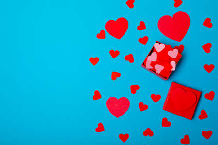 Directly above view of red hearts and gift box isolated overblue background with copy space....