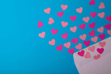 Directly above view of pink hearts coming out from envelope over blue background, copy space. valentine's day and love concept.の写真素材