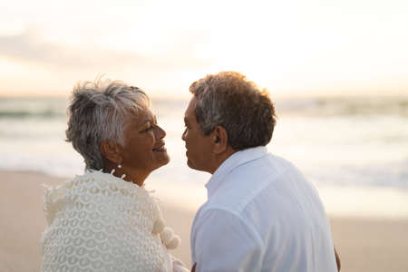 Side view of happy multiracial senior couple looking at each other romantically during sunset....