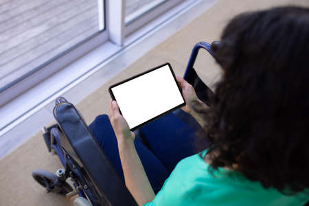 High angle view of biracial disabled woman on wheelchair using tablet pc with copy space on blank....