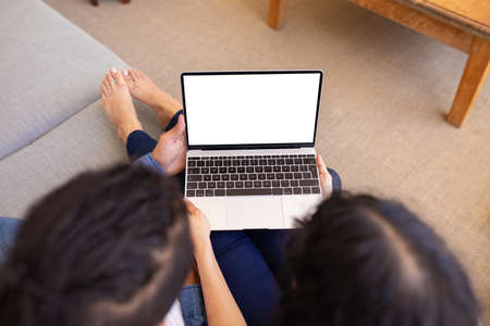 High angle view of young biracial couple using laptop with copy space on blank screen at home. technology and bonding, unaltered.の写真素材