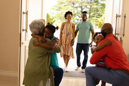African american girls hugging their grandparents on the front door at home. family, love and togetherness concept, unaltered.の写真素材