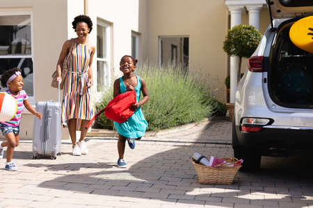 African american mother and her daughters walking towards their car outdoors. family trip and vacation concept, unaltered.の写真素材