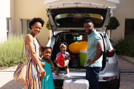 Portrait of african american family smiling while standing near their car. family trip and vacation concept, unaltered.の写真素材