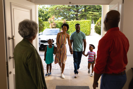 African american senior couple welcoming their family while standing on the front door at home. family, love and togetherness concept, unaltered.の写真素材