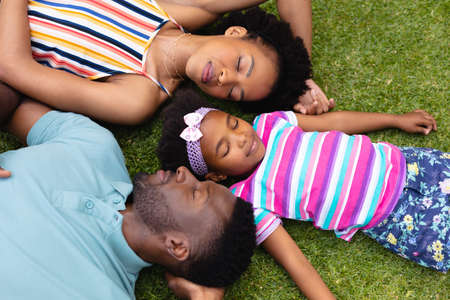Directly above view of tired african american family sleeping together on grass at garden. family, love and togetherness concept, unaltered.の写真素材