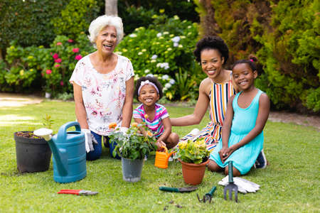 Portrait of smiling three generational female family gardening together at backyard. family, love...