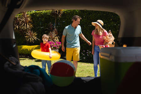 Happy caucasian family putting all their luggage in car on sunny day. family trip and vacation...