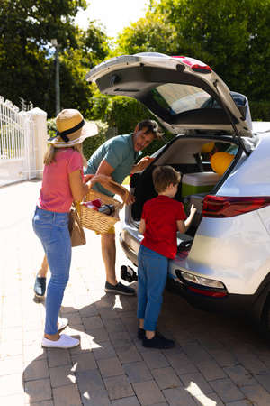 Happy caucasian family loading their luggage in their car outdoors. family trip and vacation concept, unaltered.の写真素材