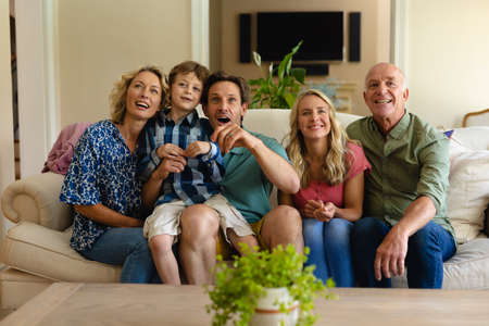 Caucasian three generation family watching tv sitting together on the couch at home. family and entertainment concept, unaltered.の写真素材