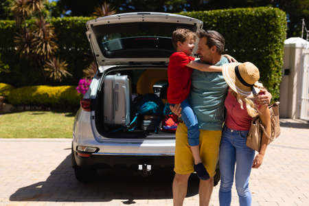 Caucasian family standing near their car smiling looking at each others. family trip and vacation concept, unaltered.の写真素材