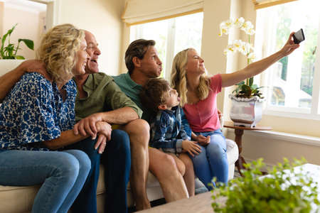 Caucasian three generation family taking a selfie while sitting on the couch at home. family, love...