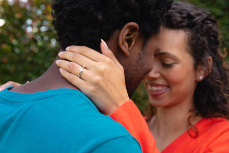 Romantic young biracial couple standing face to face in backyard garden. people, love and...