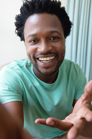 Portrait of cheerful young african american man gesturing on video call at home. people and emotions concept, unaltered.の写真素材