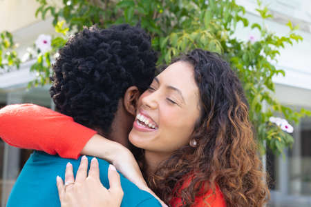 Happy young biracial woman embracing boyfriend in the garden. people, love and togetherness concept, unaltered.の写真素材