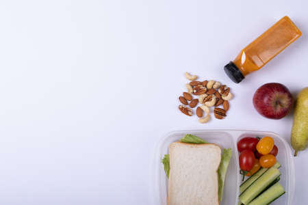 Directly above shot of healthy food and tiffin box by juice bottle over white background, copy...
