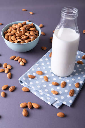 High angle view of milk bottle on napkin with almonds in bowl over gray background. unaltered, healthy food, snack, organic, drink, nut and dried food.の写真素材