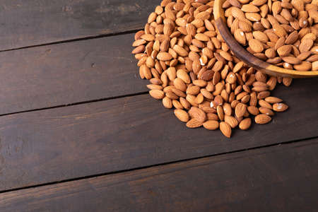 High angle view of fresh healthy almonds in wooden bowl on table with empty space. unaltered, healthy food, snack, copy space, organic, nut and dried food.の写真素材