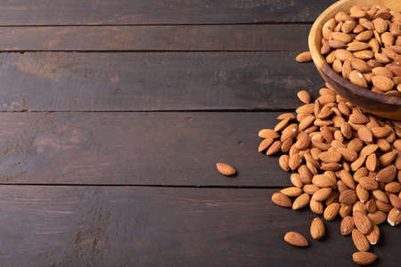 High angle view of nutritious almonds in wooden bowl on table along empty space. unaltered, healthy food, copy space, snack, organic, nut and dried food.の写真素材
