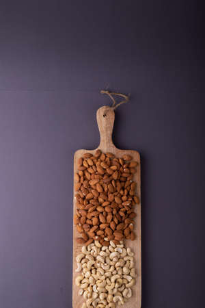 Overhead view of almonds and cashews on wooden serving board over gray background with copy space. unaltered, healthy food, snack, organic, nut and dried food.の写真素材