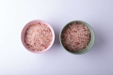 Directly above shot of pink rock salt in bowls on white background. unaltered, ingredient, food, rock salt, white and seasoning.の写真素材