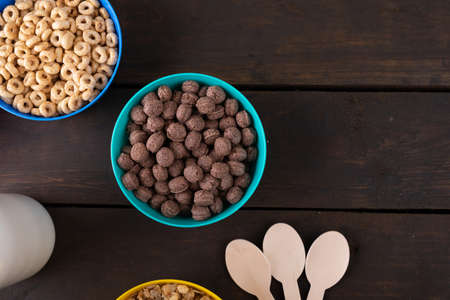 Close-up of breakfast cereals in bowls with milk bottle and spoons on table. unaltered, breakfast, healthy food, snack and food concept.の写真素材