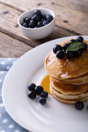 Close-up of appetizing pancakes with syrup, herb and blueberries served in plate on table. unaltered, breakfast, sweet food, organic and healthy food concept.の写真素材