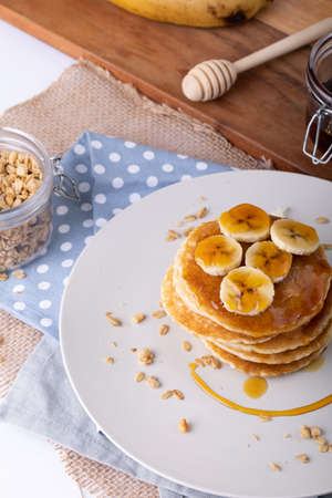 High angle view of delicious pancakes with banana slices, oats and honey in plate over napkins. unaltered, breakfast, sweet food, fruit and healthy food concept.の写真素材