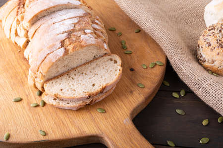High angle close-up of sliced bread loaf with seeds on wooden serving board. unaltered, healthy...