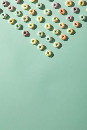 Overhead shot of ring shaped breakfast cereal on green background with blank space, copy space....