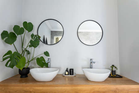 Circular shaped mirrors mounted on wall below sinks in bathroom at home. unaltered, home and interior decoration concept.の写真素材