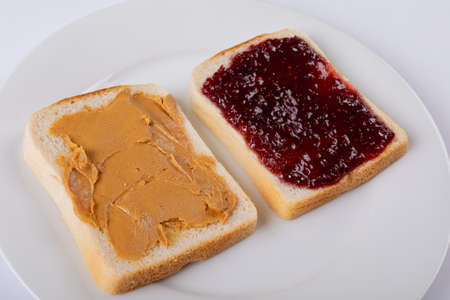 Close-up of open face peanut butter and jelly sandwich in plate on white background. unaltered, peanut butter and jelly sandwich, healthy food, preserves, preparation and breakfast.の写真素材