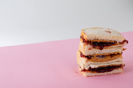 Close-up of stacked peanut butter and jelly sandwiches on table against gray background. unaltered,...