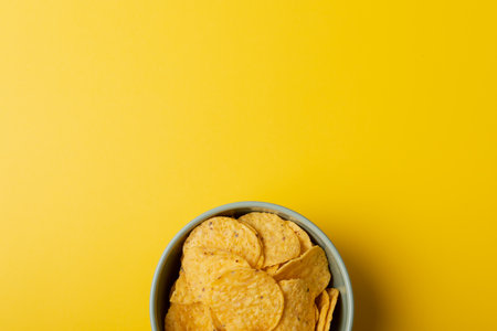 Directly above shot of chips in bowl on yellow background with copy space. unaltered, unhealthy food, snack and crunchy snack.の写真素材