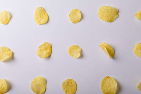 Directly above shot of potato chips arranged side by side on gray background. unaltered, unhealthy food, snack, arrangement and salty snack.の写真素材