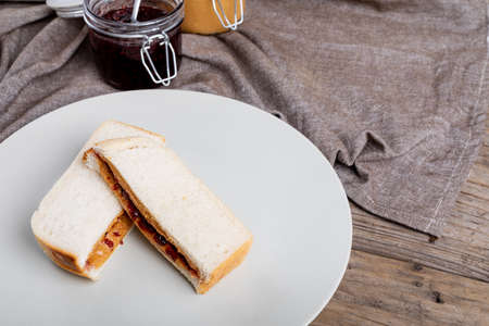 High angle view of peanut butter and jelly sandwich served in plate by jars on napkin at table....