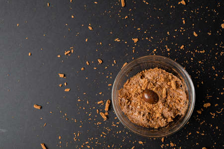 Overhead view of chocolate mousse with coated nut and shredded chocolate served in bowl on table....